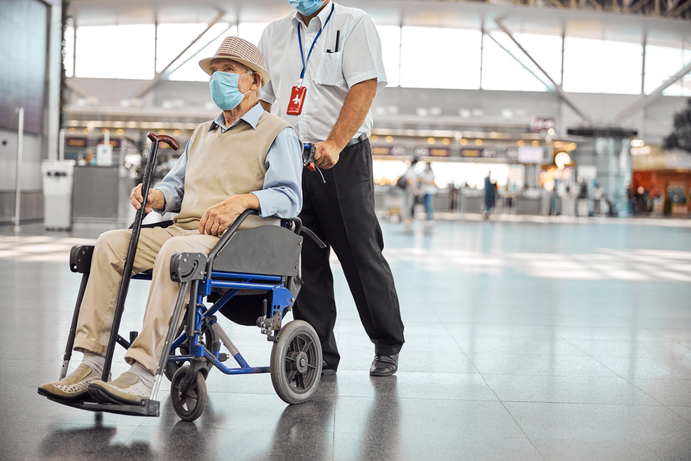 PCD pode viajar sozinha | Profissional do aeroporto ajudando um homem a se locomover na cadeira de rodas | Conexão123