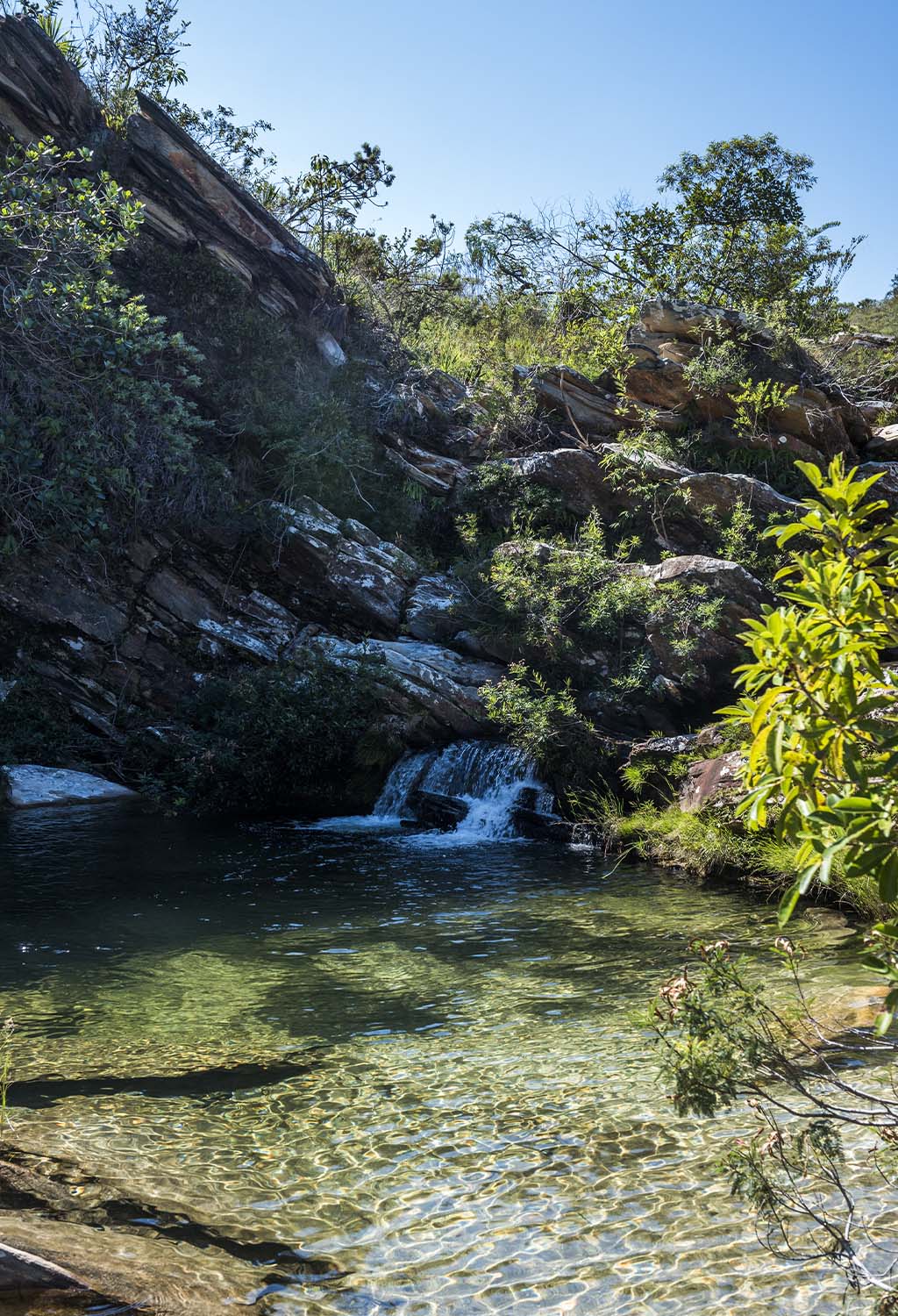 O reflexo da luz na vegetação do entorno cria um efeito esverdeado nas águas da Cachoeira da Caverna, na Serra do Cipó.