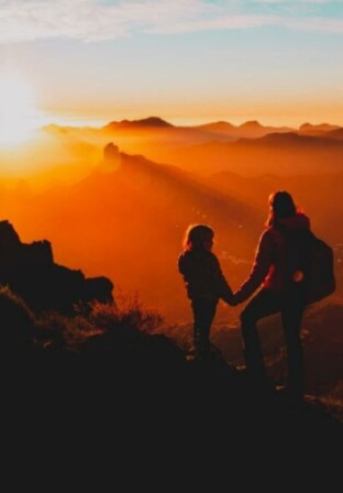 Mãe aventureira | Mãe e criança vendo por do sol na montanha | Conexão123