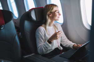 Opção de passagem aérea barata com Voos Promo da 123milhas | Mulher sentada no avião | Conexão123