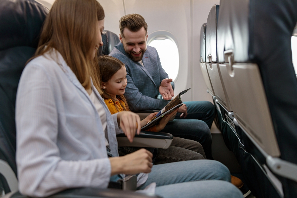 Passagens aéreas baratas: encontre voos promocionais só de ida | Casal com filha no avião | Conexão123