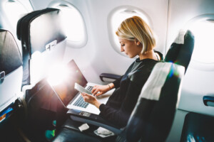 Viagens corporativas crescem e faturamento se aproxima dos números pré-pandemia | Mulher trabalhando no avião | Conexão123