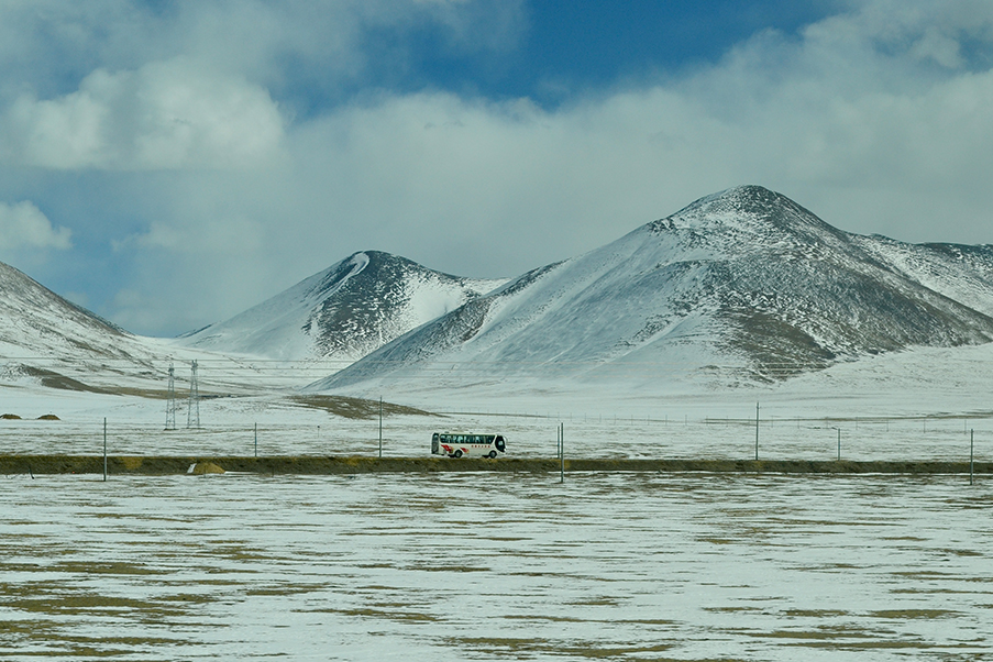 Na paisagem gelada da janela do trem, no topo do mundo, eis que surge um solitário ônibus na estrada