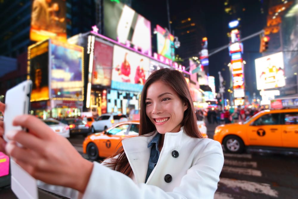 Nova parceira do Conexão123 oferece cursos de inglês para viagem | Mulher tirando selfie em Nova York | Conexão123