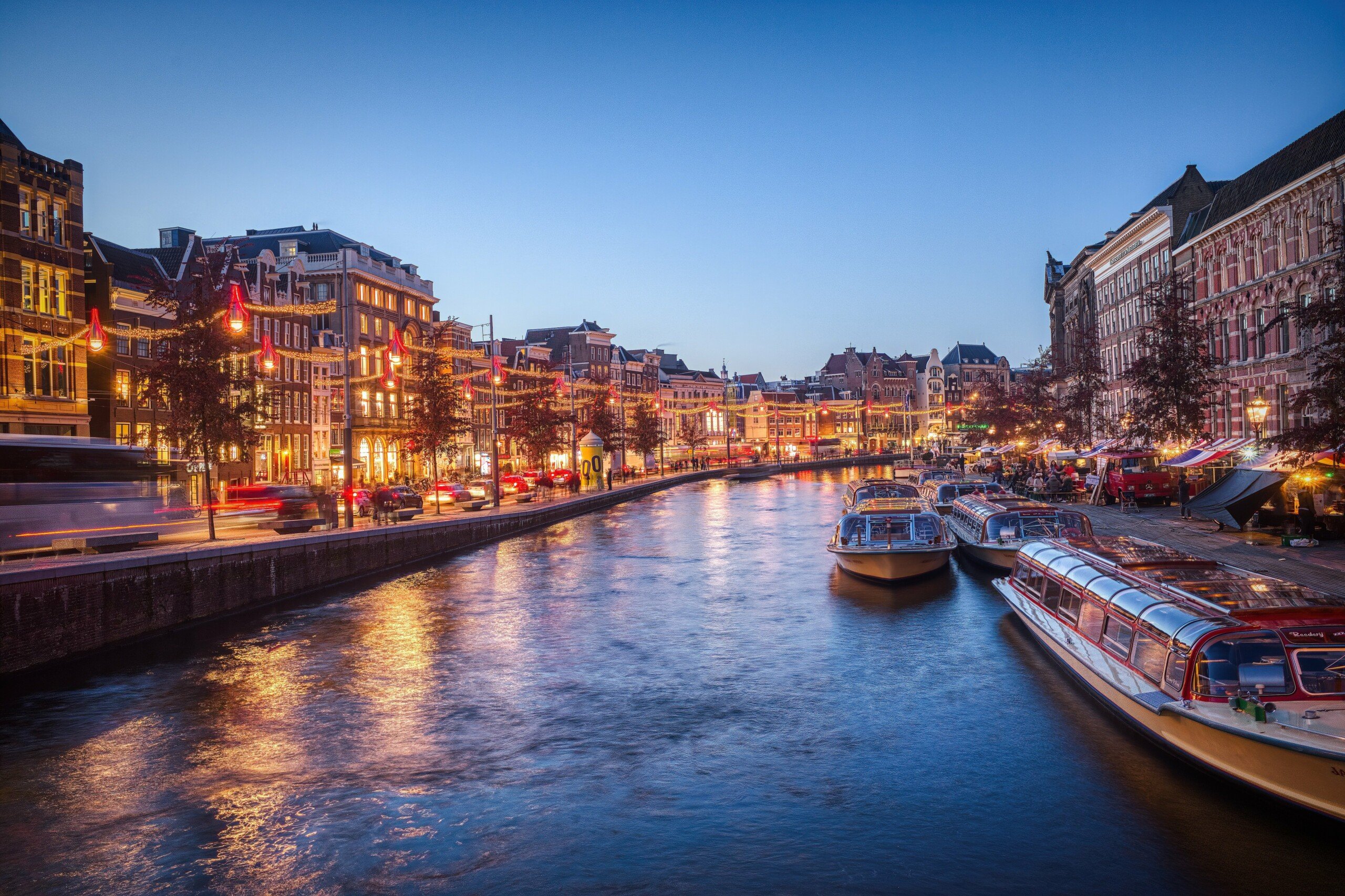 Dia Internacional da Felicidade: descubra as 10 cidades mais felizes do mundo | Cidade de Amsterdã com vista para um de seus canais, iluminada pelo cair da tarde | Conexão123
