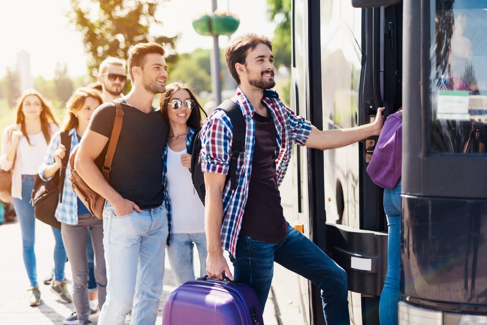Aproveite os feriados para viajar de ônibus com conforto e segurança | Grupo de viajantes se preparando para entrar no ônibus | Conexão123