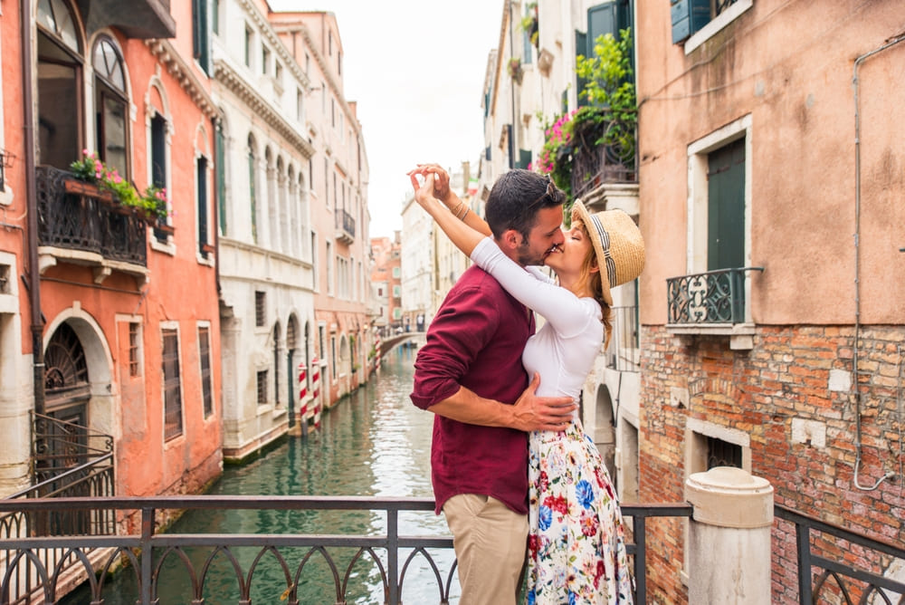 Confira cinco destinos românticos para comemorar o Dia Internacional do Beijo | Jovem casal beijando em Veneza | Conexão123