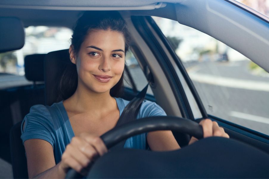 Dia do Motorista: Oito itens essenciais para uma viagem de carro | Mulher fazendo um sinal de positivo enquanto guia o seu carro | Conexão123
