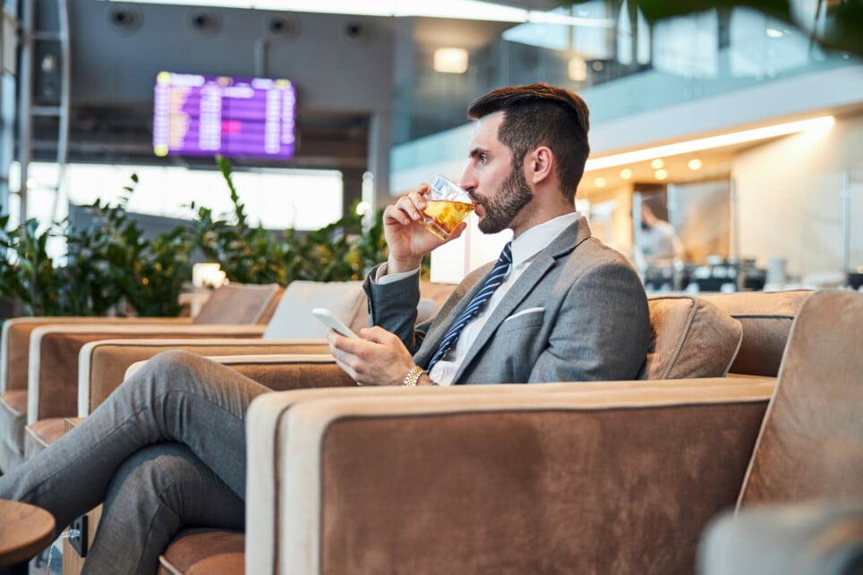 Salas VIP de Aeroportos: o refúgio luxuoso dos viajantes | Homem de negócios tomando um whisky enquanto aguarda em uma sala VIP de aeroporto | Conexão123
