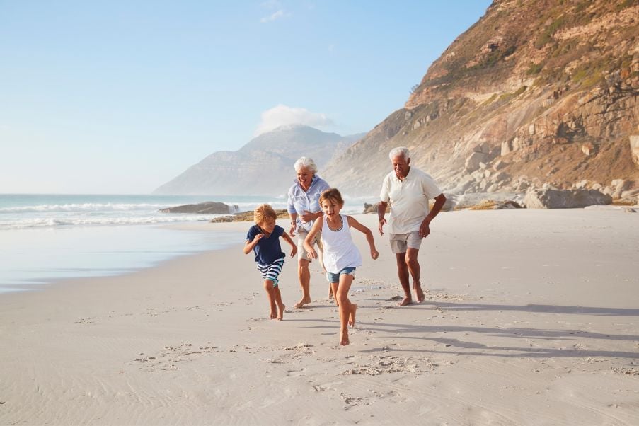 Dia dos Avós: destinos para diferentes tipos de avós | Avós brincando com netos na praia | Conexão123