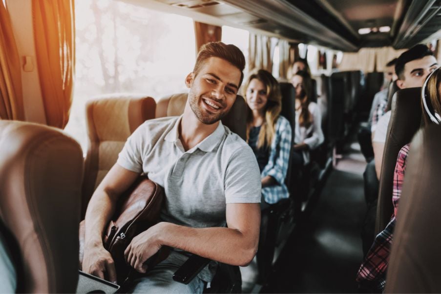 Destinos para viajar de ônibus: locais que agradam todos os perfis | Foto de pessoas animadas em um ônibus de viagem | Conexão123