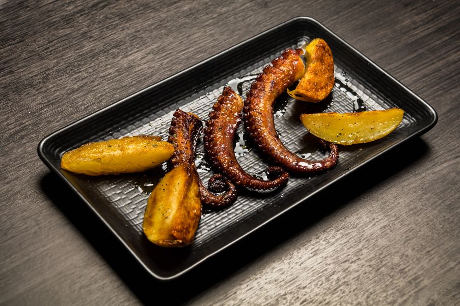 Lugares para comer em Sevilha | Imagem de um prato com tentáculos de polvo grelhados com batatas | 123milhas